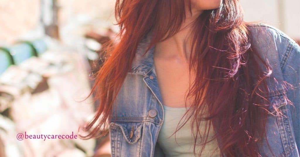 An image of a woman's upper body with jean jacket that shows her red hair to show the benefit of Henna for hair