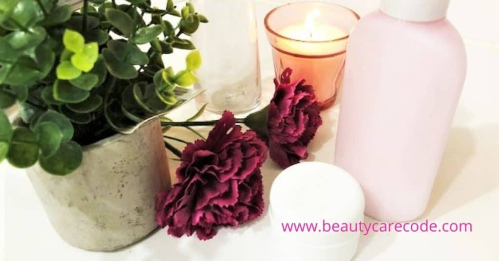 an image of green plant and pink flower beside a candle, a lotion and a white small cream container to describe if bakuchiol is your best anti-ageing skincare