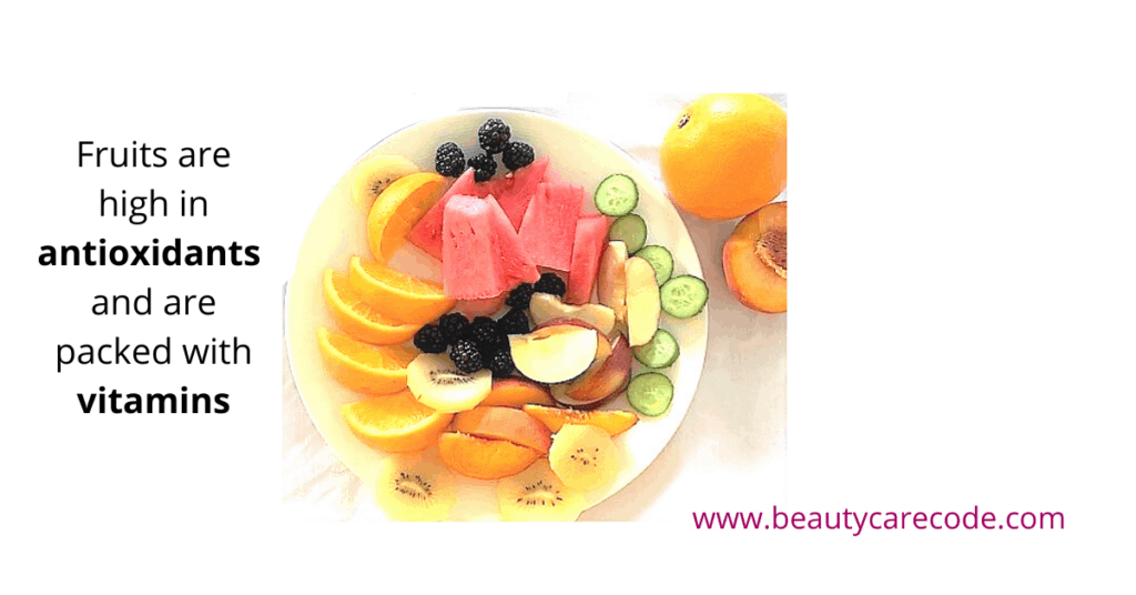An image of a plate with slices of orange, apple, watermelon, kiwi, cucumber and a few balck berry in a white background to discuss the role of diet in glowing skin. 