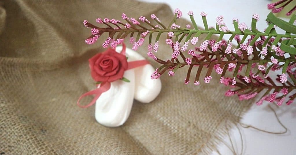 An image of two soap bars with a pink ruban around them and a pink flower in a brown background